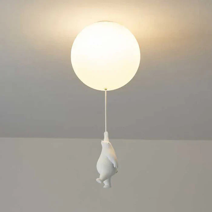 Weiße Deckenleuchte mit rundem Lampenschirm und hängender Pinguinfigur, modernes Design.