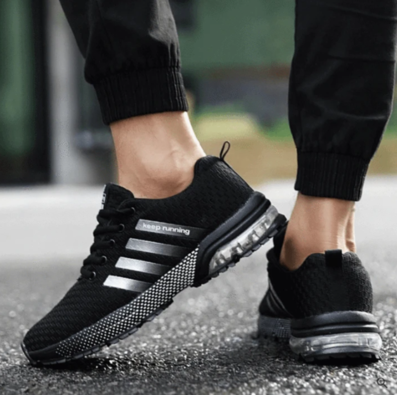 Schwarze Herren-Laufschuhe mit Luftpolstersohle, atmungsaktiv, sportlich, Straßenhintergrund.