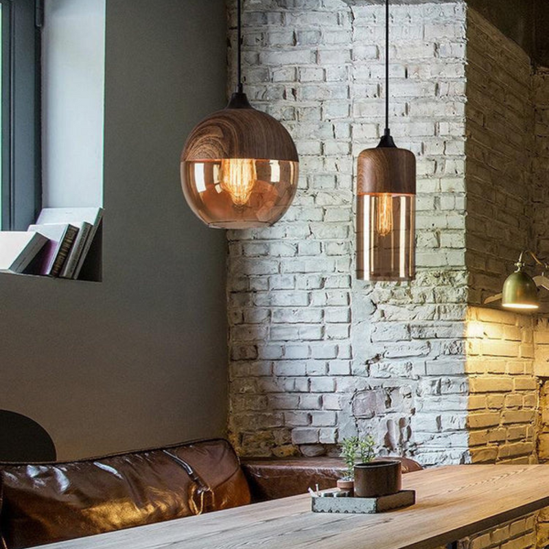 Moderne Hängelampen aus Holz und Glas über einem Esstisch, industrielle Loft-Einrichtung.