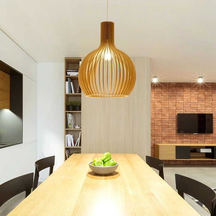 Moderne Esszimmer mit hölzernem Esstisch, goldener Pendelleuchte und Ziegelwand.