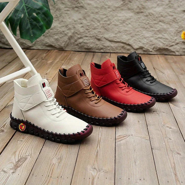 Vier Paar Lederstiefel in Weiß, Braun, Rot und Schwarz auf Holzboden, modisch und robust.