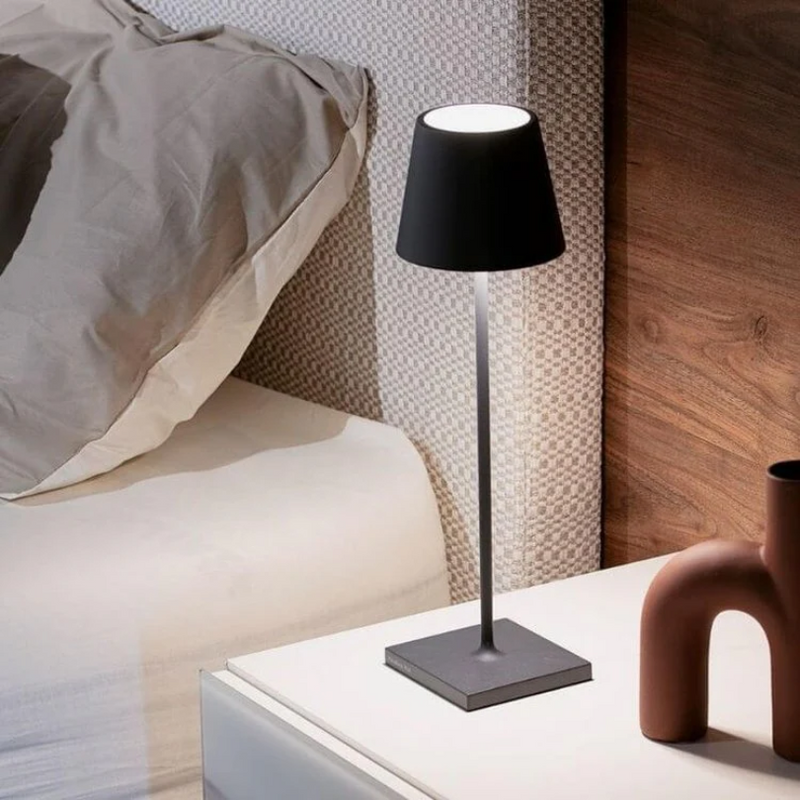 Schwarze Tischlampe auf Nachttisch neben Bett, modernes Design, Schlafzimmerbeleuchtung.