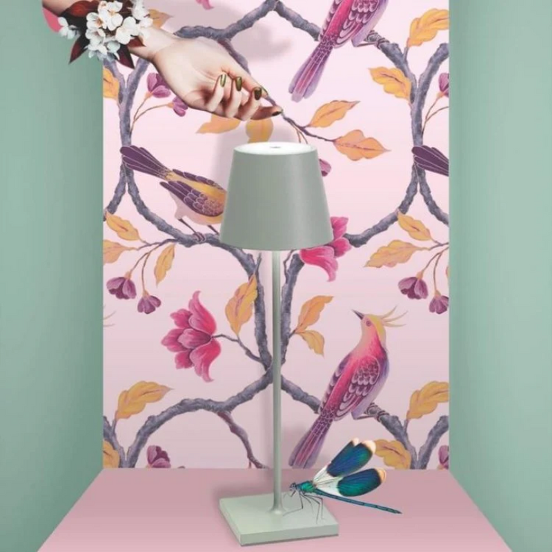 Graue Tischlampe vor rosa Tapete mit Vögeln und Blumen, modernes Innendesign.