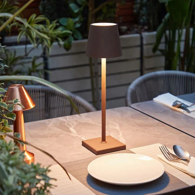 Moderne Tischlampe aus Metall, schwarz, auf Esstisch im Freien, stilvolle Beleuchtung.