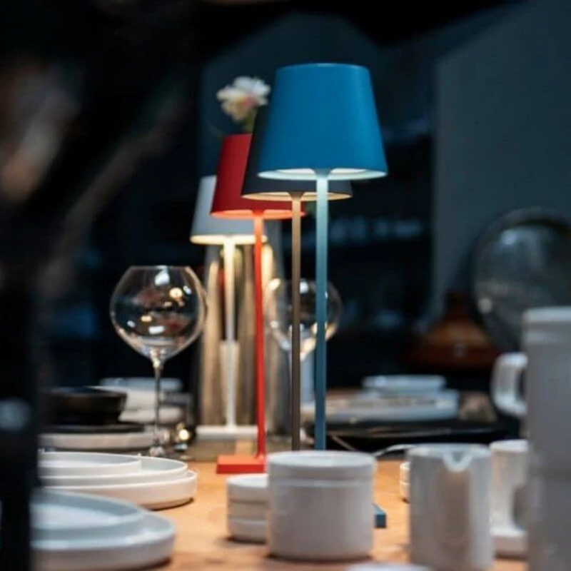 Moderne Tischlampen in Blau und Rot auf gedecktem Tisch, stilvolle Beleuchtung, Inneneinrichtung.