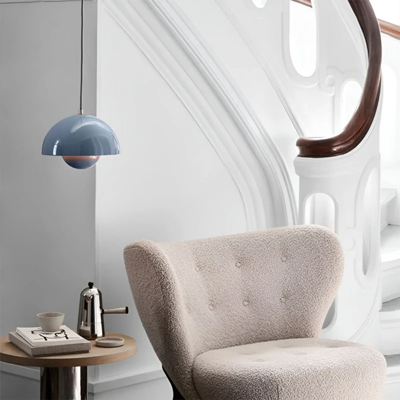 Blaue Pendelleuchte, cremefarbener Sessel, modernes Interieur, skandinavisches Design.