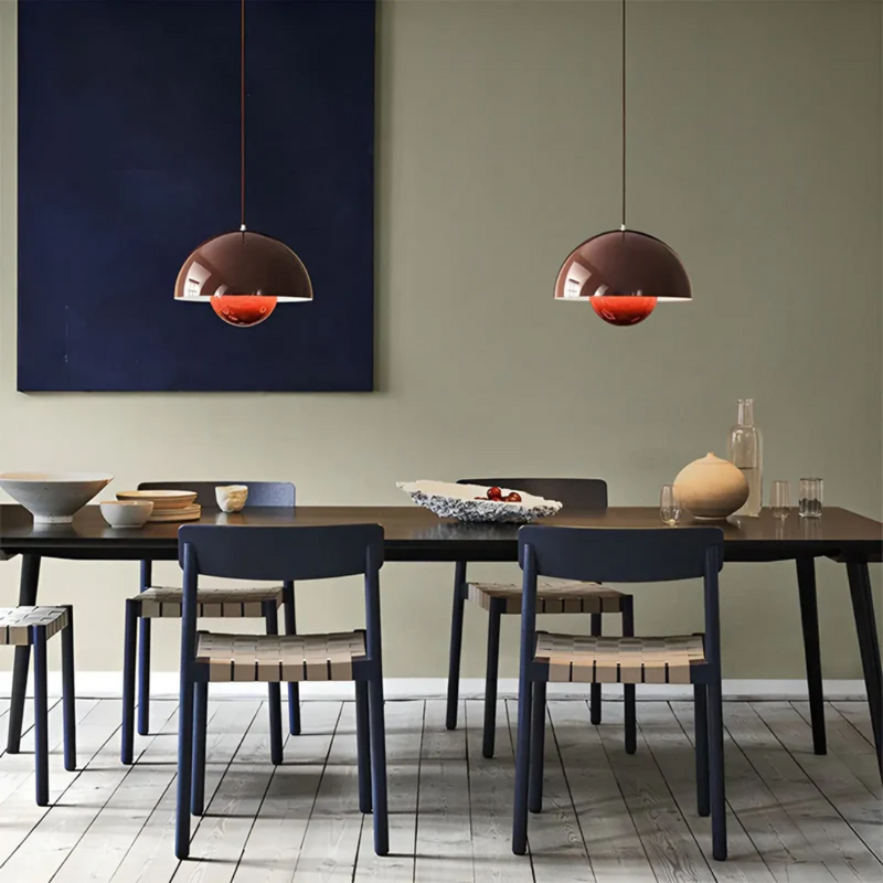 Moderne Esszimmer mit braunen Pendelleuchten, Holztisch, blauen Stühlen und Dekoration.