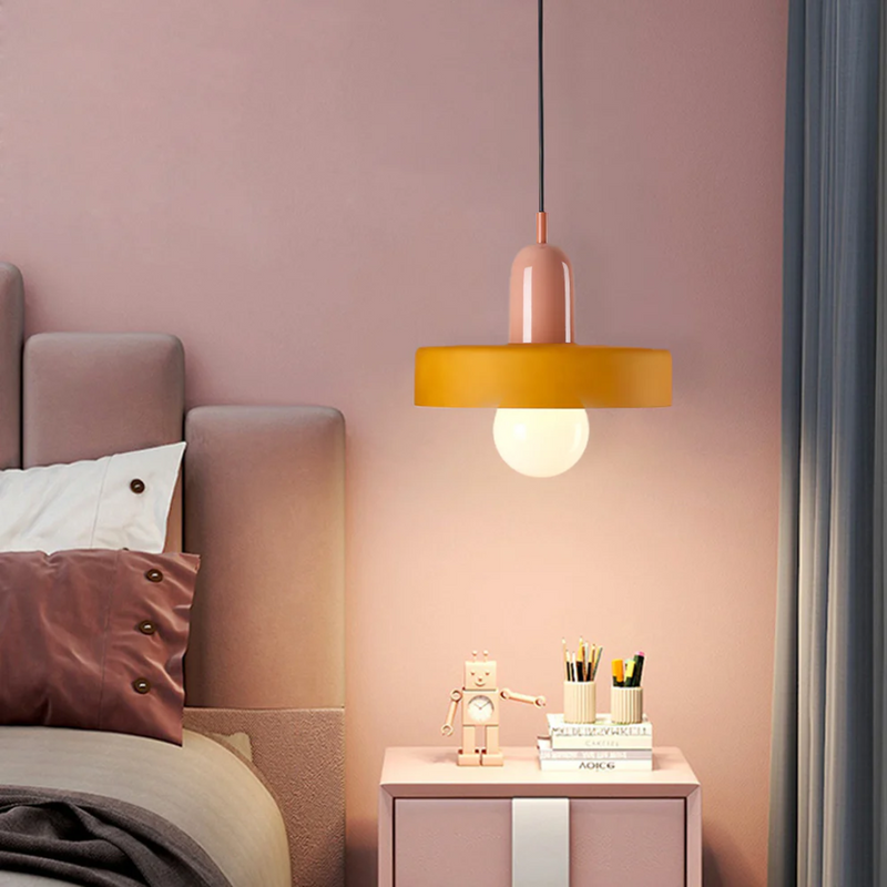 Hängelampe modern rosa-gelb über Nachttisch im Schlafzimmer mit Deko und Vorhang.