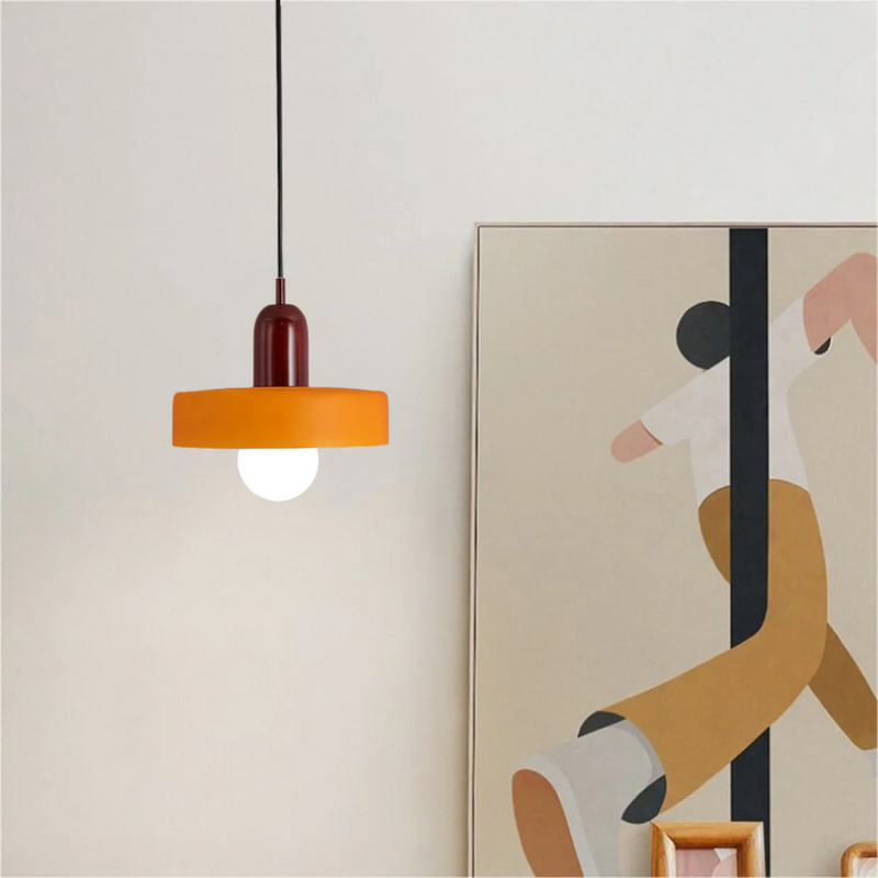 Orange Hängelampe mit Glühbirne neben modernem Gemälde, minimalistisches Innendesign.