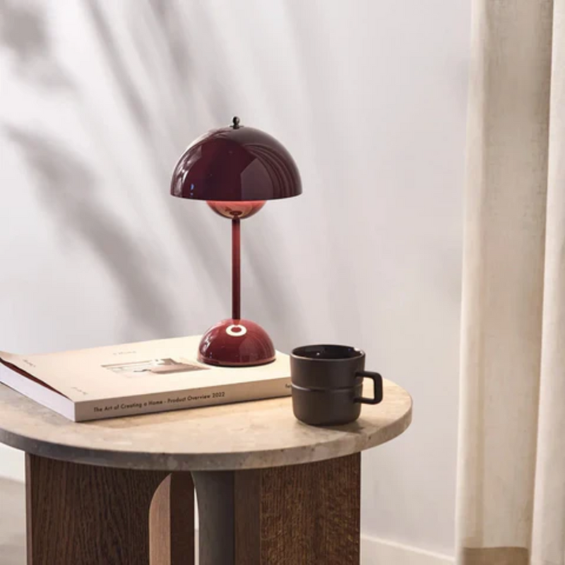 Rote Tischlampe auf Holztisch mit Buch und schwarzer Tasse, modernes Innendesign, Wohnzimmer.
