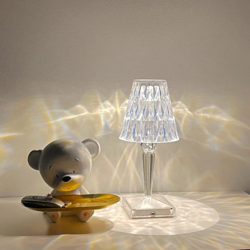 Graue Bärenfigur mit Skateboard neben Kristalltischlampe auf weißem Hintergrund.