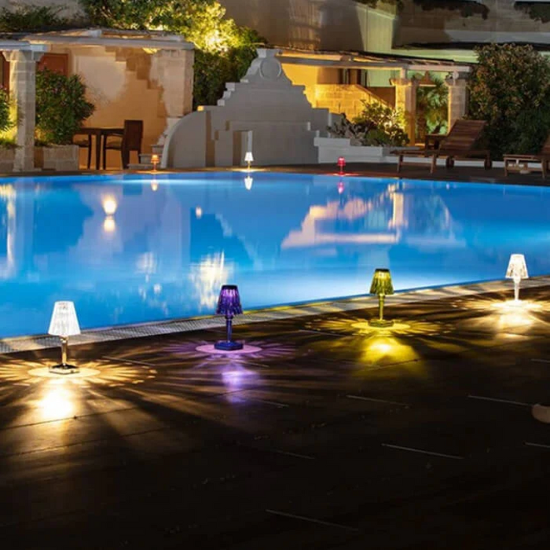 Luxuriöser Pool bei Nacht mit farbigen LED-Lampen, stimmungsvolle Beleuchtung, Außenbereich.