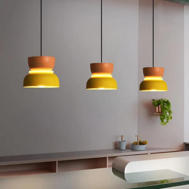 Drei gelbe Hängelampen aus Metall über modernem Küchentresen, minimalistisches Design.