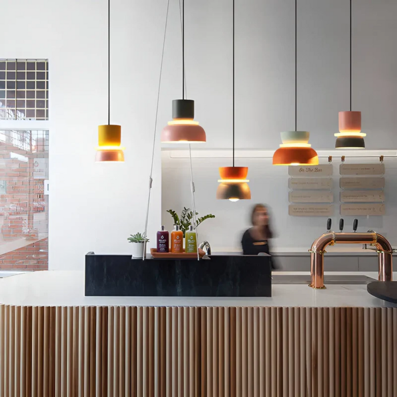 Moderne bunte Hängelampen über Theke in stilvollem Café-Interieur, skandinavisches Design.