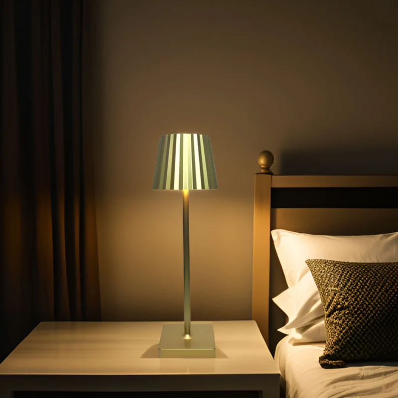Moderne Nachttischlampe aus Metall, goldfarben, auf weißem Tisch neben Bett im Schlafzimmer.