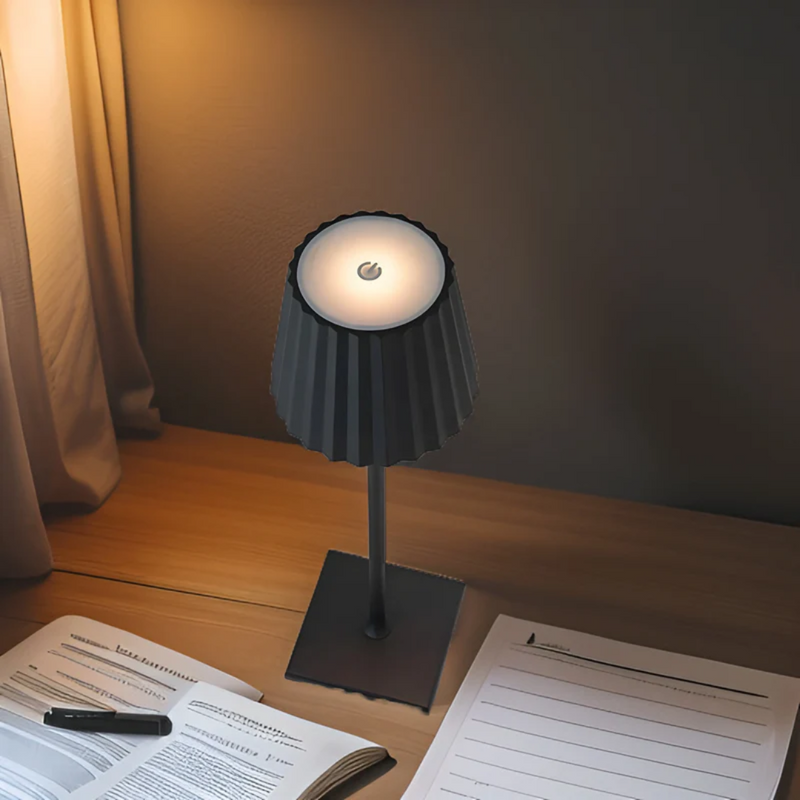 Schwarze LED-Tischlampe auf Holzschreibtisch, modernes Design, beleuchtet, neben Büchern.