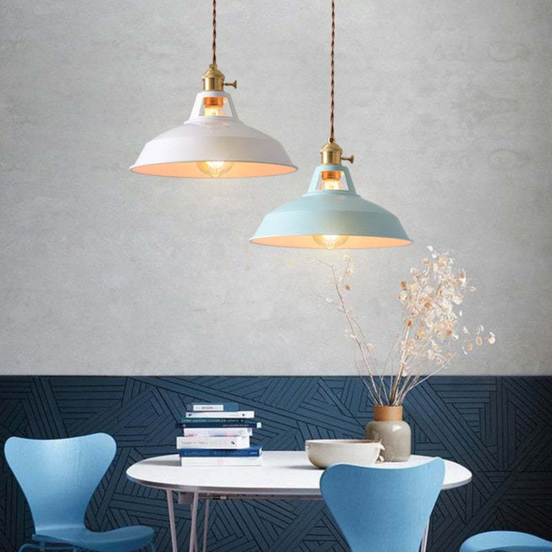 Zwei Hängelampen im Vintage-Stil über einem runden Tisch mit blauen Stühlen und Dekoration.