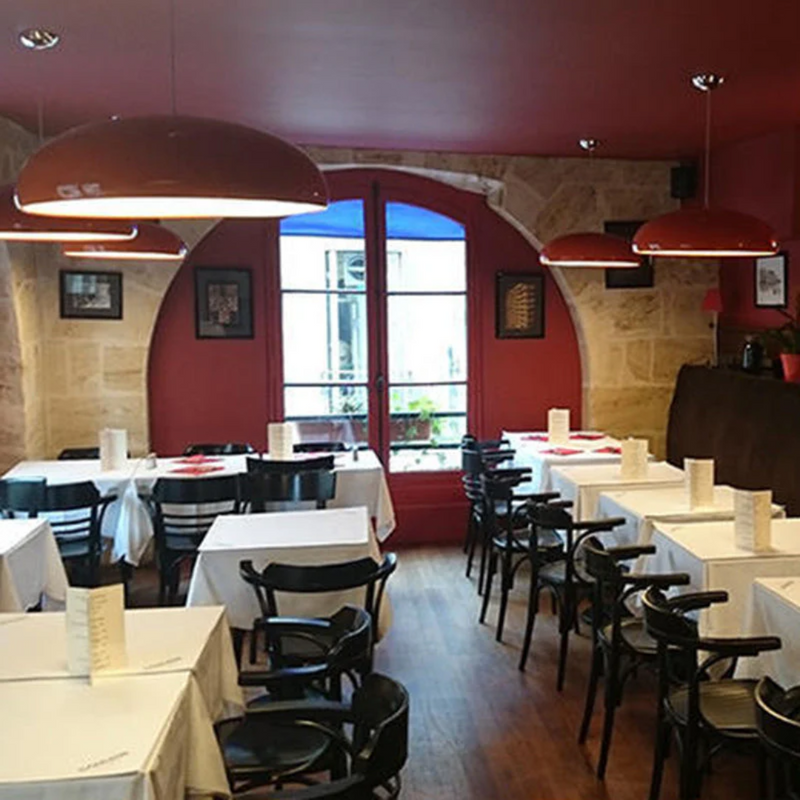 Gemütliches Restaurant mit roten Wänden, schwarzen Stühlen und weißen Tischdecken.