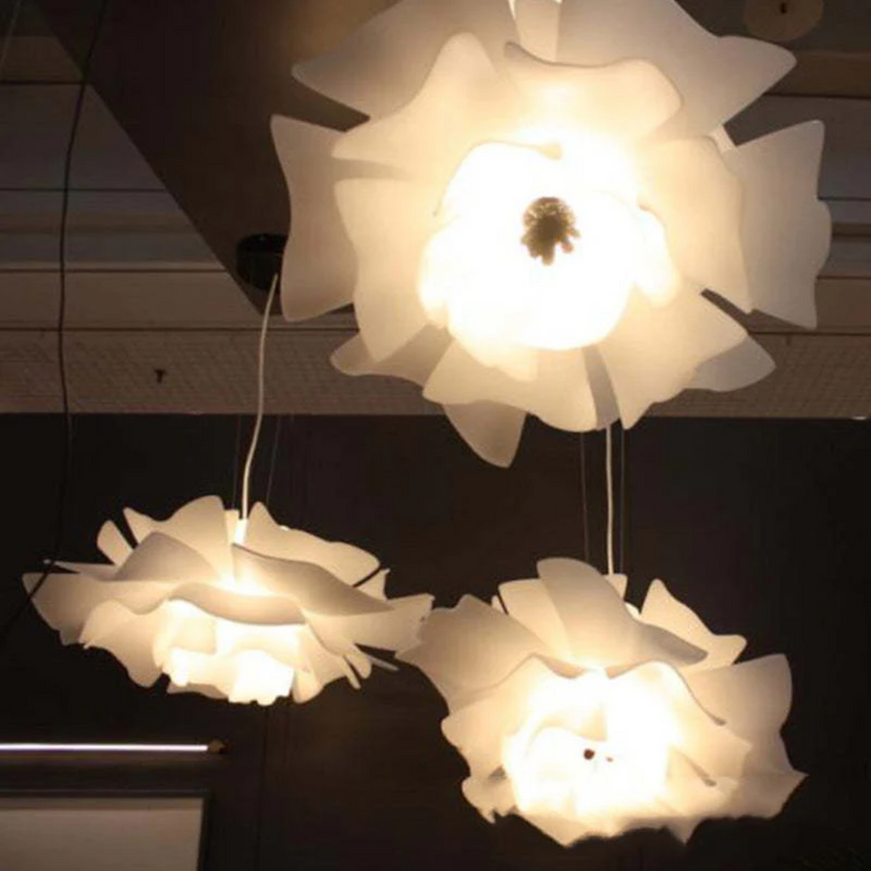 Drei weiße, blumenförmige Deckenleuchten aus Kunststoff, modern, hängend, beleuchtet.