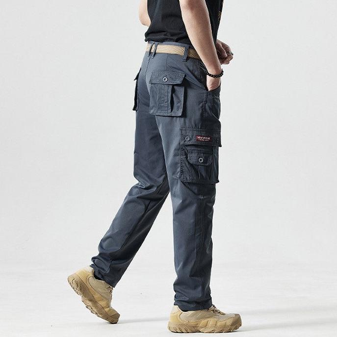 Mann in grauer taktischer Hose mit Seitentaschen, beige Stiefel, Outdoor-Bekleidung.