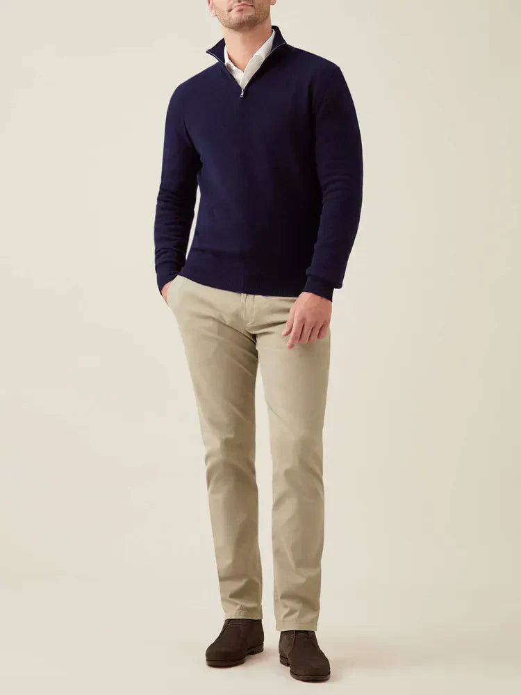 Mann trägt dunkelblauen Kaschmir-Pullover mit Reißverschluss, beige Hose, braune Schuhe.
