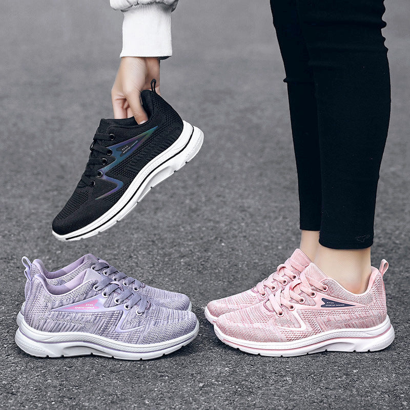 Drei Paar Sportschuhe, schwarz, lila, rosa, atmungsaktiv, Damen, auf Asphalt.