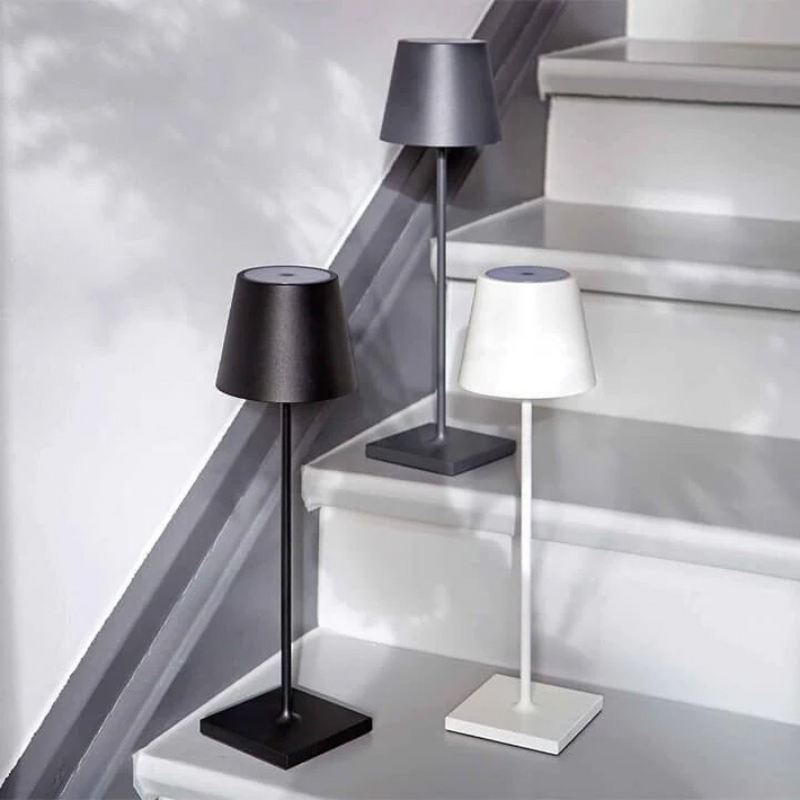 Drei moderne Tischlampen in Schwarz, Grau und Weiß auf Treppe, minimalistisches Design.