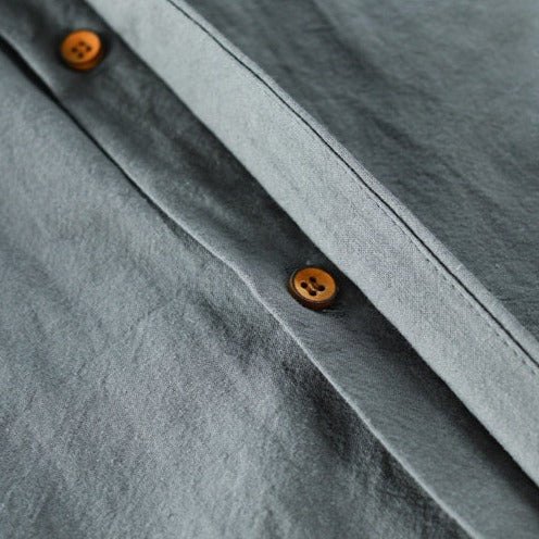 Graues Leinenhemd mit braunen Knöpfen, Nahaufnahme, hochwertige Herrenmode, stilvoll.