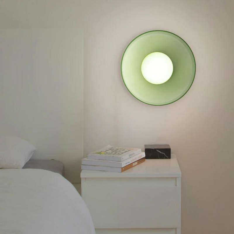 Grüne Wandleuchte im modernen Schlafzimmer, rundes Design, über weißem Nachttisch.