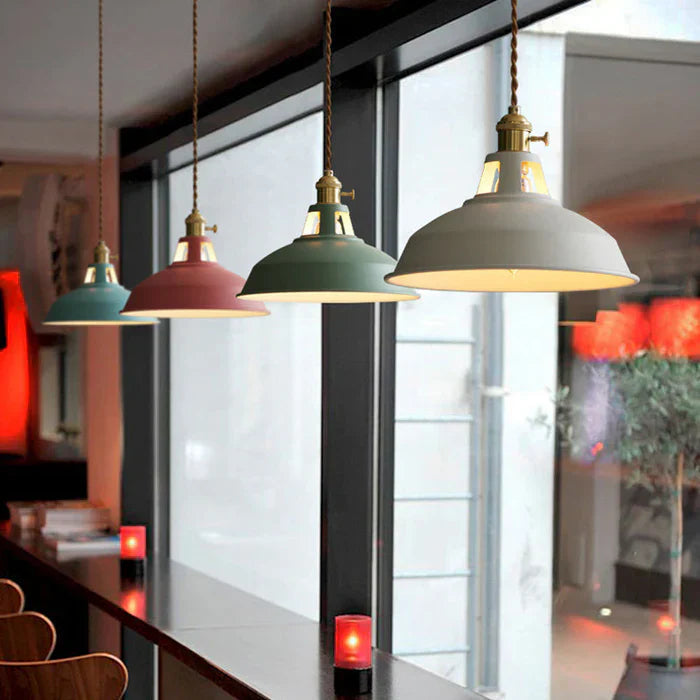 Vier bunte Pendelleuchten im industriellen Stil über einer Theke in modernem Café.