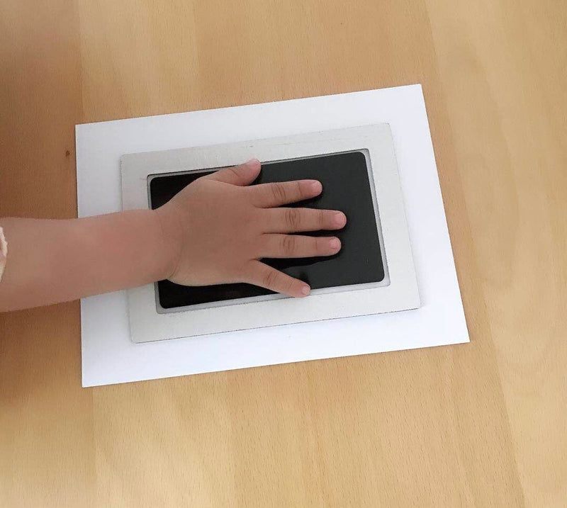 Kindergartenkind Handabdruck auf schwarzem Stempelkissen, Holzuntergrund, DIY Bastelprojekt.