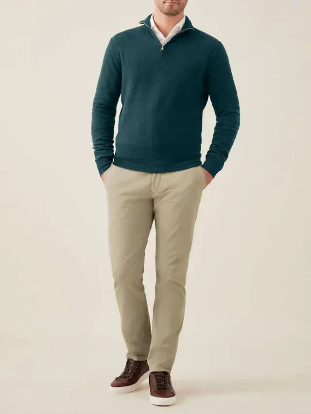 Mann trägt grünen Kaschmir-Pullover mit Reißverschluss, beige Hose, braune Schuhe.