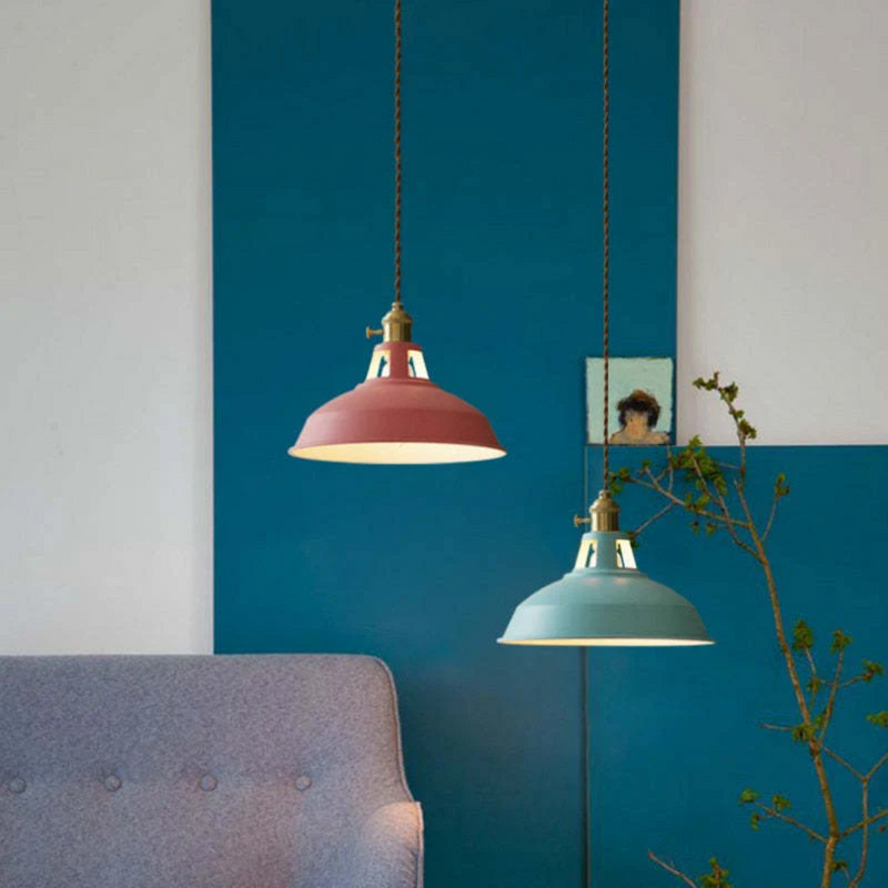 Zwei Hängelampen in Rosa und Blau über grauem Sofa, modernes Wohnzimmerdesign.