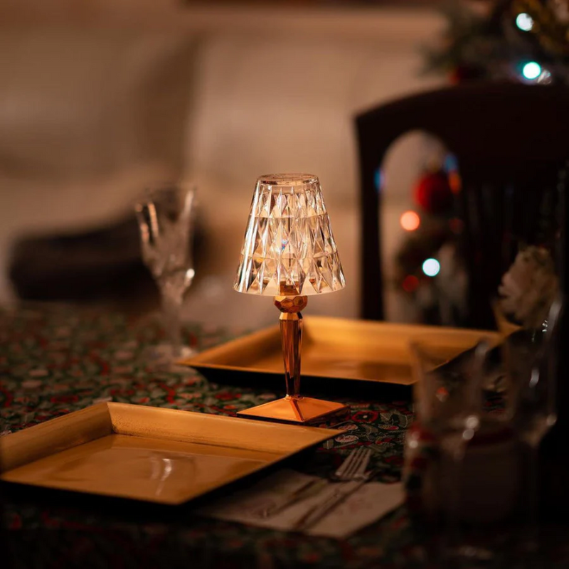 Kristall-Tischlampe auf festlich gedecktem Tisch, warmes Licht, elegante Dekoration.