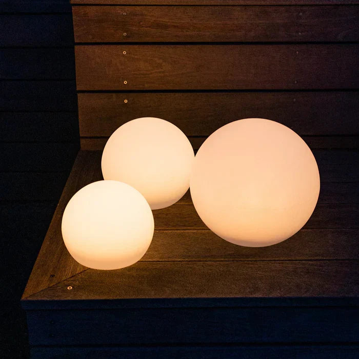 Drei leuchtende LED-Kugellampen auf Holztreppe, warmweiß, für Gartenbeleuchtung.
