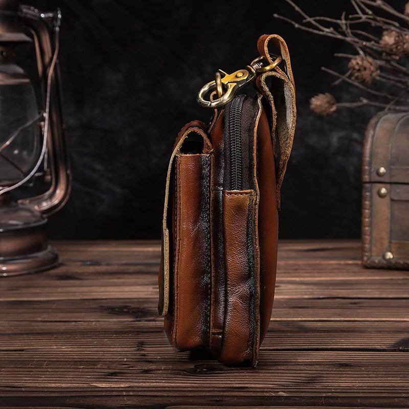 Braune Herren-Ledertasche, vintage, mit Reißverschluss und Karabinerhaken, auf Holztisch.