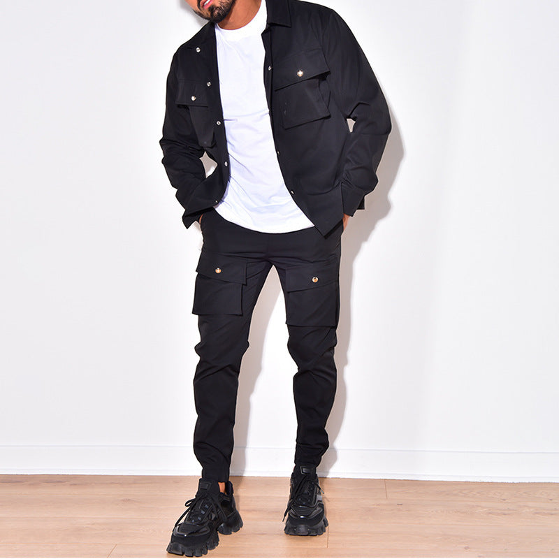 Mann in schwarzer Cargo-Jacke und Hose, weißes T-Shirt, schwarze Sneaker, modisch, urban.