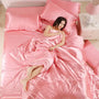 Frau in rosa Satin-Bettwäsche, luxuriöses Schlafzimmer, elegante Einrichtung, gemütliches Ambiente.