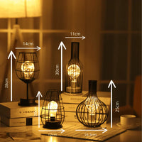 Vier dekorative LED-Lampen in schwarzem Metallkäfig-Design auf einem Tisch, warmes Licht.