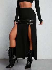 Frau in schwarzem Maxirock mit Schnallen, hoher Schlitz, schwarze Stiefel, modisch, elegant.