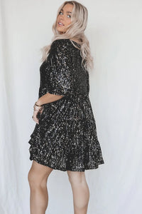 Frau in schwarzem Paillettenkleid, blondes Haar, modisches Abendoutfit, glamouröses Design.