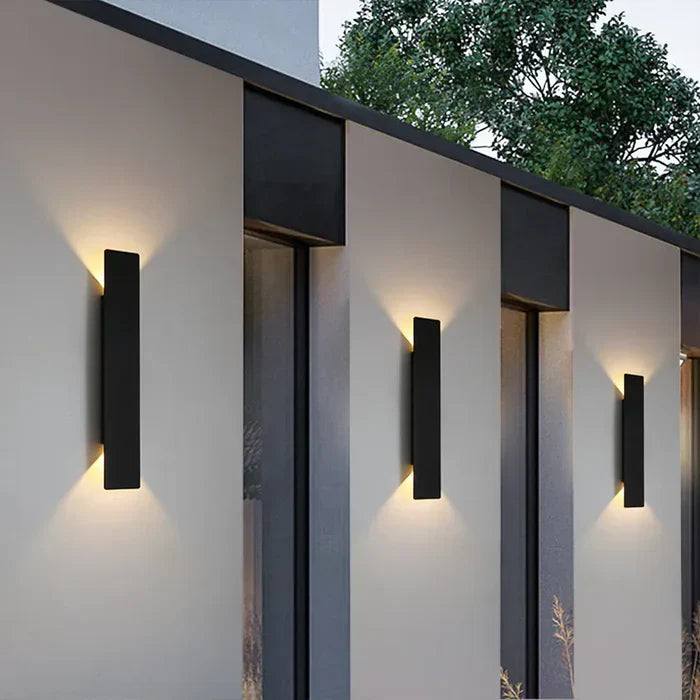 Moderne schwarze Außenwandleuchte, rechteckig, LED, an weißer Hauswand montiert.
