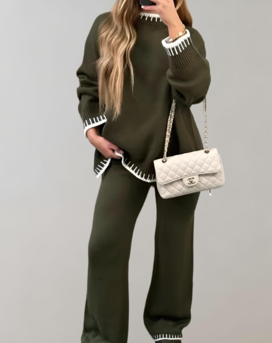 Frau in olivgrünem Zweiteiler, Strick, mit weißer Handtasche, modisch, elegant, nachhaltig.