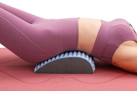 Frau in lila Sportkleidung auf Rückentrainer, Yoga-Matte, Fitness, Rückenstütze, Dehnung.