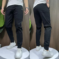 Schwarze Jogginghose Herren, Slim Fit, Baumwolle, sportlich, bequem, mit weißen Sneakers.