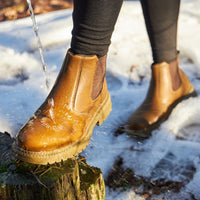 Braune wasserdichte Chelsea-Boots aus Leder im Schnee, ideal für Winter und Outdoor-Aktivitäten.