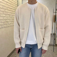 Mann in cremefarbener Strickjacke, weißem T-Shirt und Jeans, lässige Herrenmode.
