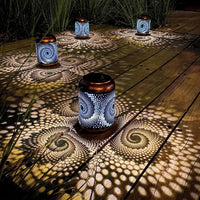 Solarbetriebene Gartenlaternen aus Metall, spiralförmiges Muster, stimmungsvolle Beleuchtung, Nacht.