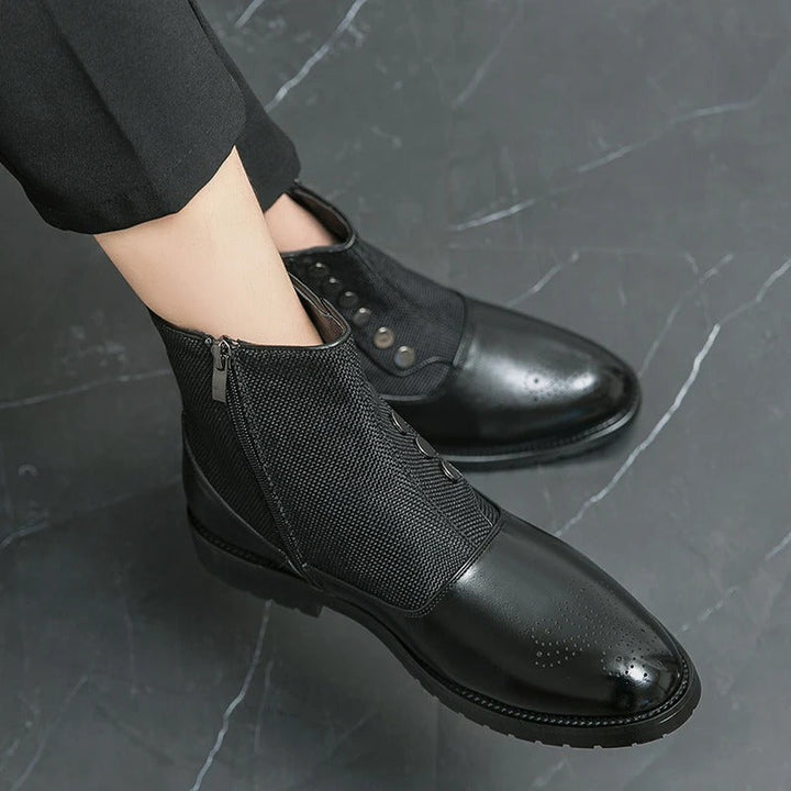 Schwarze Herrenstiefeletten aus Leder, elegant, mit Reißverschluss, auf grauem Marmorboden.