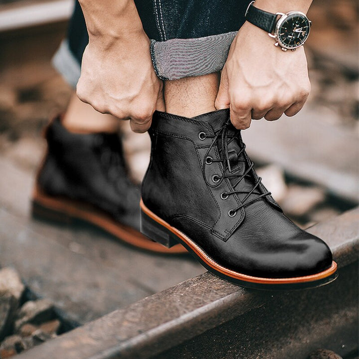 Schwarze Lederstiefel für Herren, geschnürt, modisch, robust, auf Bahngleisen.